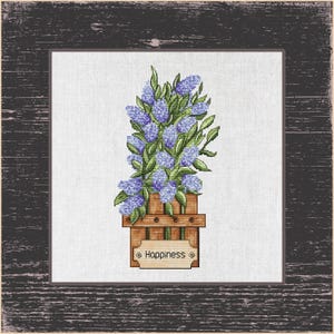 Könnte beinhalten: Kreuzstich-Kunstwerk mit Lavendelblüten in einem Holzpflanzer, mit dem Wort "Happiness" auf einem kleinen Schild. Das Kunstwerk ist in einem rustikalen, dunklen Holzrahmen gerahmt.