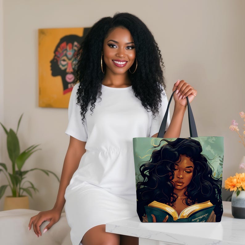 May include: A tote bag featuring an illustration of a woman with long, dark hair reading a book. The bag has black handles and a light green background. The woman in the image is wearing a white dress.