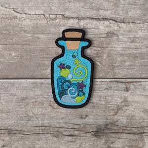 May include: An embroidered patch shaped like a glass bottle with a cork stopper. The bottle is filled with light blue liquid, dark blue wave patterns, purple starfish, a yellow spiral, a green circle, and small white bubbles, all outlined in black.