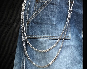 Könnte beinhalten: Eine silberne Kette mit zwei Strängen, die von einem Paar Gürtelschlaufen an einer blauen Jeans hängt.