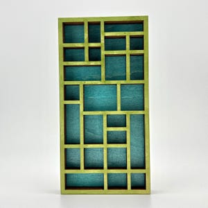 May include: A rectangular wooden display shelf featuring a grid of various sized compartments. The outer frame and internal dividers are painted in a light lime green, while the back panel of each individual section is a deep teal blue color.