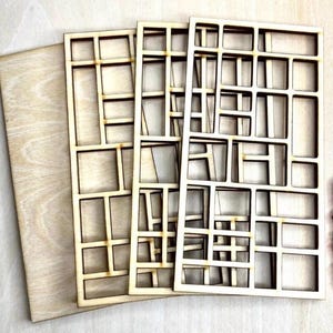 May include: Three rectangular light-colored wooden panels featuring a laser-cut grid pattern of various sized open squares and rectangles. The panels are stacked slightly offset, revealing the natural wood grain and smooth, light brown edges.