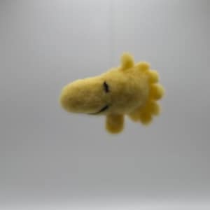 Peut inclure: Une marionnette de main en feutre jaune en forme d'oiseau avec un visage souriant.