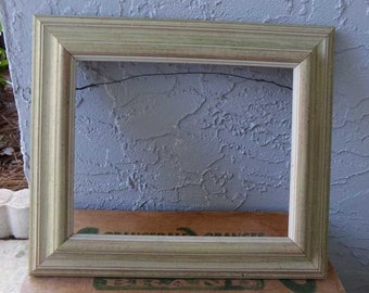 May include: A light green and white wood picture frame with a simple design. The frame is sitting on a wooden surface.