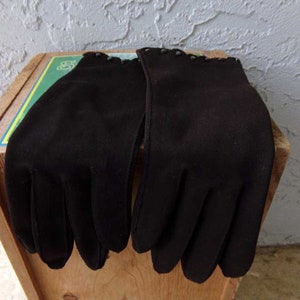 Pode incluir: Um par de luvas pretas com uma guarni&ccedil;&atilde;o decorativa em torno do pulso.