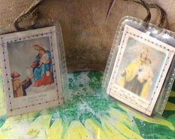 May include: Two vintage religious prayer cards in clear plastic holders. One card depicts Mary and Jesus, the other shows Our Lady of Mt. Carmel. Both cards have text. Each card has a woven cord for hanging.
