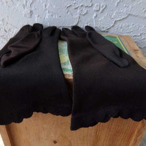 Pode incluir: Dois pares de luvas pretas de comprimento do cotovelo com bordas festoneadas.