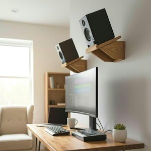 May include: A home office setup featuring a wooden desk with a computer, keyboard, and a small potted plant. Two black speakers are mounted on wooden shelves on the wall. A laptop and a mug are also on the desk.
