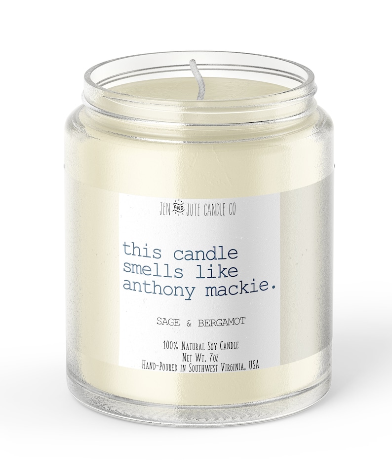 May include: A clear glass jar candle with a white label that reads "JEN & JUTE CANDLE CO" and "this candle smells like anthony mackie." The label also says "SAGE & BERGAMOT", "100% NATURAL SOY CANDLE", "NET WT. 7oz", and "HAND-POURED IN SOUTHWEST VIRGINIA, USA".