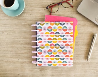 May include: A pink and yellow binder with a colorful geometric pattern of circles and stars. The binder has a clear plastic cover and a metal ring binding system.