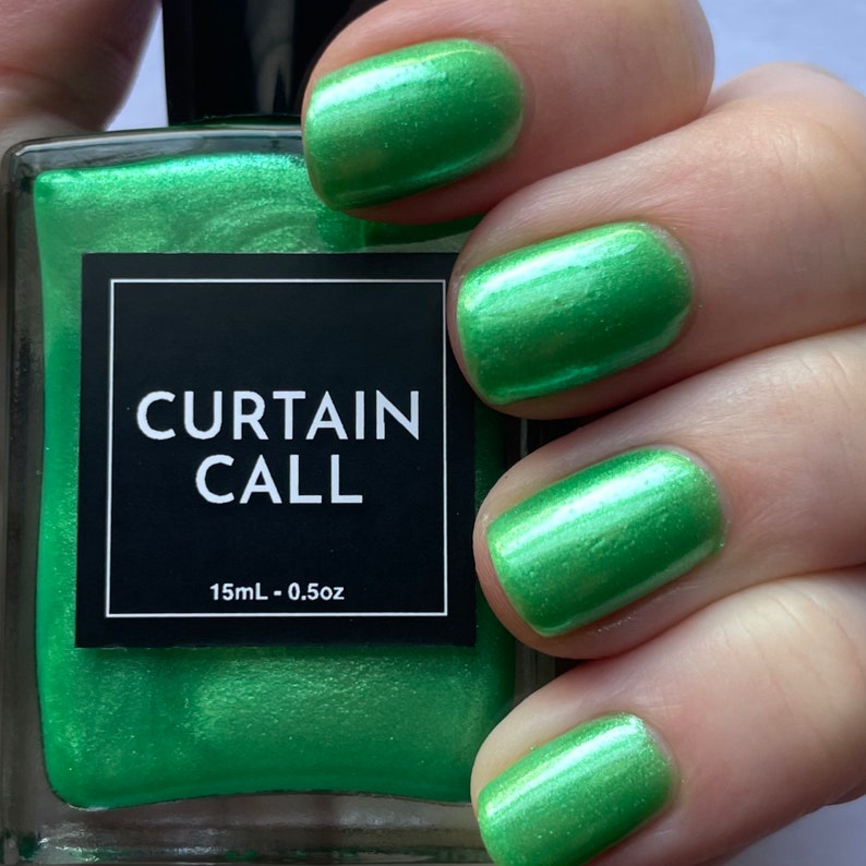 May include: A bottle of green nail polish with a metallic finish. The bottle is labeled "CURTAIN CALL" and "15mL - 0.5oz".
