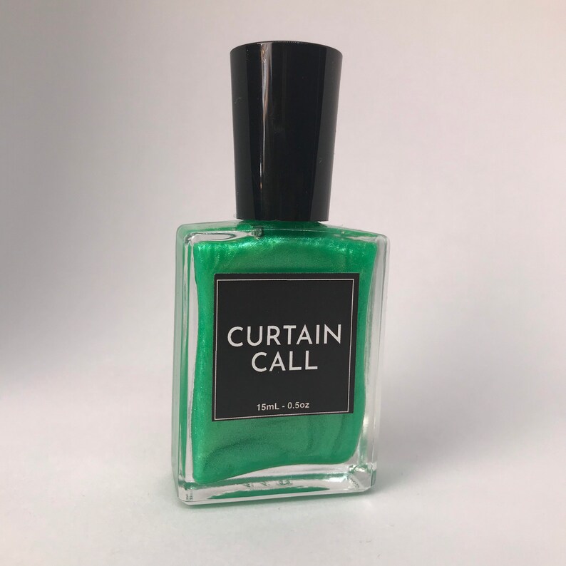 May include: A green nail polish bottle with a black cap. The bottle has a label that says "CURTAIN CALL" and "15mL - 0.5oz".