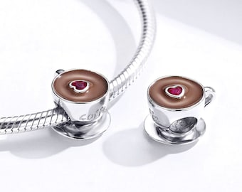 Op de afbeelding: Twee zilveren armbandjes met een koffiekopje bedel. De bedel is een zilveren kopje met bruine vloeistof en een rood hart in het midden. Het kopje heeft de tekst "Coffee" aan de zijkant.