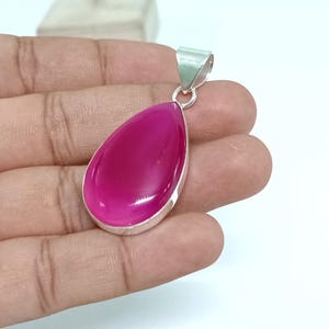 May include: A teardrop-shaped pendant with a pink gemstone set in silver.