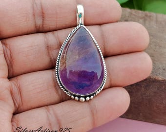 May include: A teardrop-shaped pendant with a purple amethyst gemstone set in a silver frame. The pendant is on a hand, with the text "Silver Artisan 925" visible below.