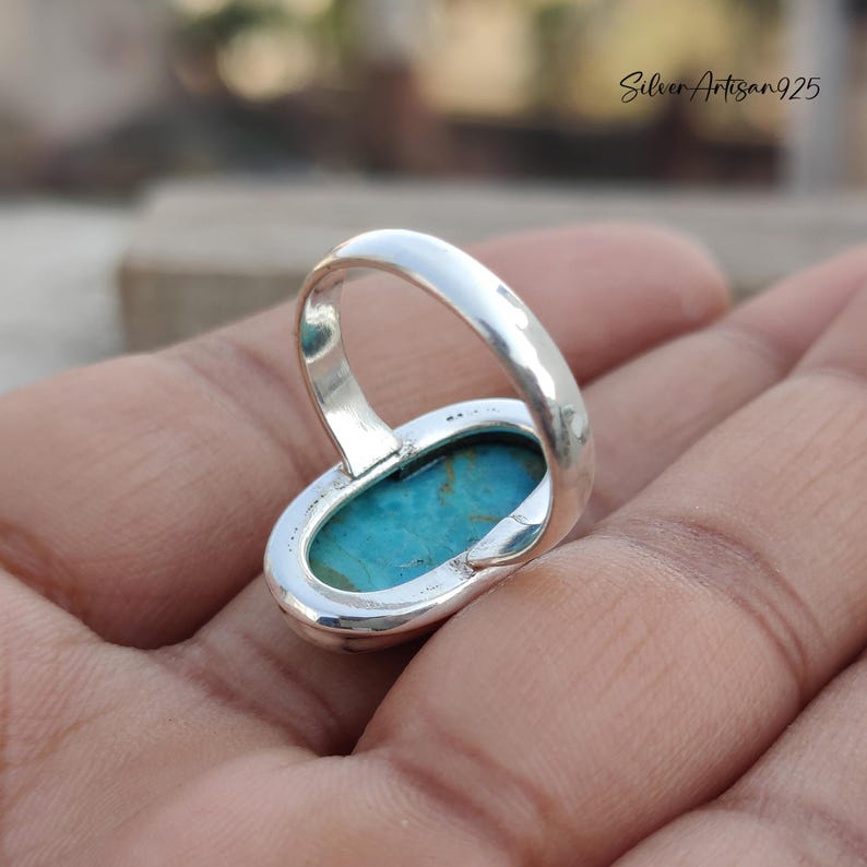 May include: A silver ring with a turquoise oval gemstone. The ring is set in a simple, elegant design.