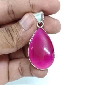 May include: A teardrop-shaped pendant with a pink gemstone set in silver.