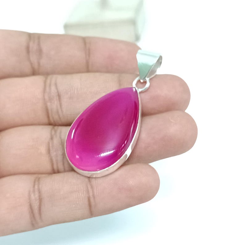 May include: A teardrop-shaped pendant with a pink agate gemstone set in sterling silver.