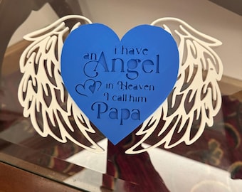 May include: A blue heart-shaped memorial with the text "I have an Angel in Heaven I call him Papa." The heart is surrounded by white angel wings. The design is likely made of layered materials.