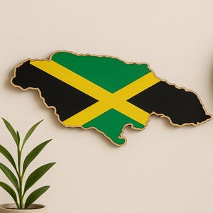 Könnte beinhalten: Wanddekoration aus Holz in Form von Jamaika, bemalt mit der jamaikanischen Flagge. Das Design der Flagge zeigt ein gelbes diagonales Kreuz über grünen und schwarzen Abschnitten. Im Hintergrund ist eine Uhr zu sehen.