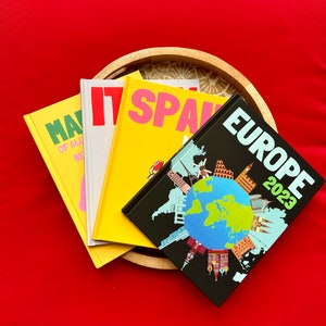 Puede incluir: Cuatro diarios de viaje con cubiertas coloridas. Las cubiertas presentan las palabras "Map of All", "Spain", "Europe 2023" y un mapa de Europa.