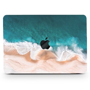 Könnte beinhalten: Eine Laptop-Hülle mit einem Strandmotiv: türkisfarbenes Wasser, weiße Wellen und sandiger Strand. Das schwarze Apple-Logo ist sichtbar. Das Design bedeckt die gesamte Oberseite des Laptops.