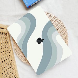 Puede incluir: Una piel de portátil blanca con un diseño abstracto de ondas azules y grises. El logotipo de Apple es visible en la piel.