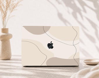May include: A laptop skin featuring an abstract design with organic, flowing shapes in shades of beige, cream, and taupe, accented by thin, continuous black lines. The black Apple logo is visible in the center of the laptop lid.