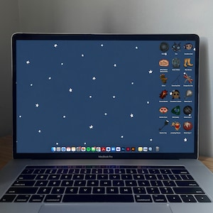 May include: A laptop computer with a dark blue background and white stars. The screen displays a variety of icons, including a cat, a boot, a glove, a beetle, a key, and a red eye. The laptop has a silver keyboard and trackpad.