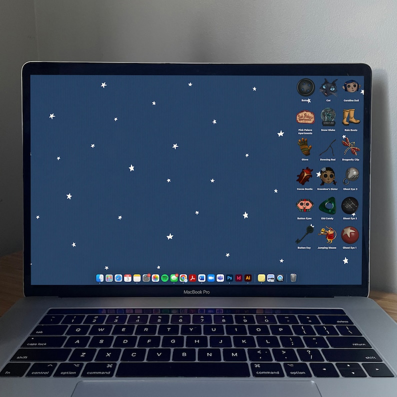 May include: A laptop computer with a dark blue background and white stars. The screen displays a variety of icons, including a cat, a boot, a glove, a beetle, a key, and a red eye. The laptop has a silver keyboard and trackpad.