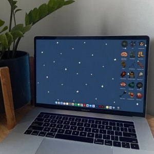 May include: A laptop computer with a dark blue background and white stars. The screen displays a variety of icons, including a cat, a boot, a ghost eye, and a jumping boy. The laptop has a black keyboard and a silver case.