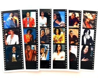 May include: Six vertical bookmarks designed to resemble strips of 35mm film, each featuring three distinct photographic portraits of Michael Jackson in various outfits, poses, and expressions, arranged in a grid-like sequence on a white background.