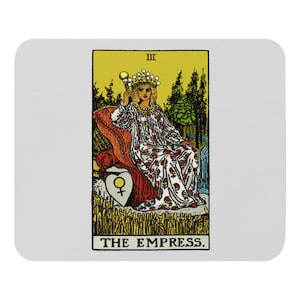 Puede incluir: Una alfombrilla de ratón rectangular con la carta del tarot de la Emperatriz. La carta representa a una mujer con un vestido blanco con estampados florales rojos, sentada en un trono rojo. El fondo es amarillo con árboles y el texto "THE EMPRESS."