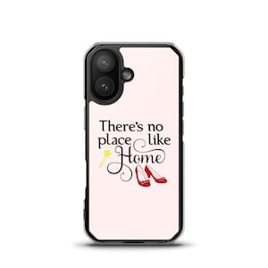 May include: A phone case with a light pink background featuring the text "There's no place like Home" in black script. A yellow wand and red shoes are also displayed. The case has a black border.