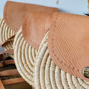 May include: Three round straw bags with brown leather flaps. The bags have a woven design and are lined with a decorative stitch.