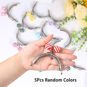 May include: A collection of silver-toned purse clasps with colorful, striped ball charms. The clasps are in various colors, including red, pink, green, yellow, and blue. The text "5Pcs Random Colors" is displayed at the bottom of the image.
