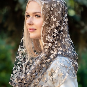 May include: A black lace veil with gold embroidery. The veil is delicate and has a scalloped edge.