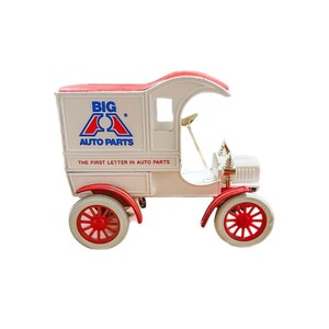 May include: White toy delivery truck with red wheels and a red and blue "BIG A AUTO PARTS" logo on the side. The truck has a white cab and a red roof. The text "THE FIRST LETTER IN AUTO PARTS" is printed below the logo.