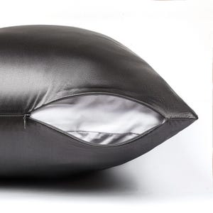 May include: A dark charcoal gray pillowcase with a smooth, lustrous finish. The pillowcase features a partially open side seam revealing a white interior lining and a small, matching dark gray zipper pull integrated into the seam closure.