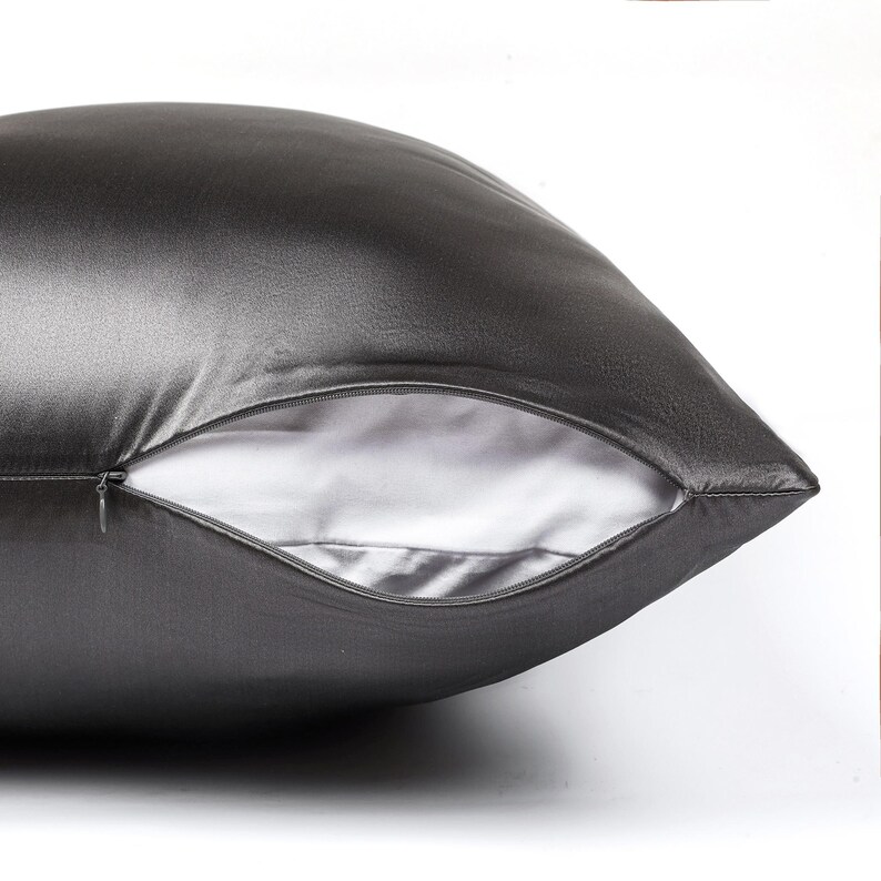 May include: A dark charcoal gray pillowcase with a smooth, lustrous finish. The pillowcase features a partially open side seam revealing a white interior lining and a small, matching dark gray zipper pull integrated into the seam closure.