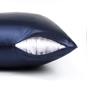 May include: A dark navy blue pillowcase with a smooth, satin-like finish. The pillowcase features a concealed zipper closure along the side, which is partially open to reveal a plain white fabric interior lining visible within the opening.