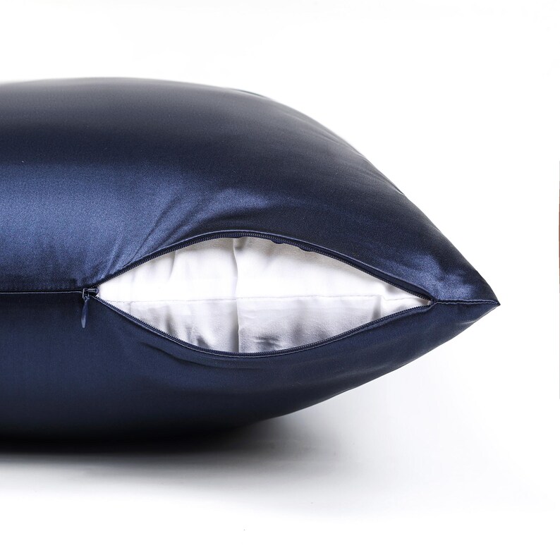 May include: A dark navy blue pillowcase with a smooth, satin-like finish. The pillowcase features a concealed zipper closure along the side, which is partially open to reveal a plain white fabric interior lining visible within the opening.