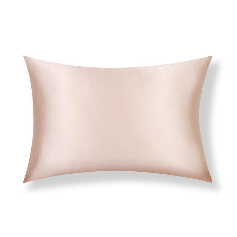 May include: A rectangular pillowcase in a solid, light blush pink color. The fabric has a smooth, lustrous, and reflective surface texture, indicating a satin or silk-like finish. The pillowcase is presented flat with clean, straight edges.