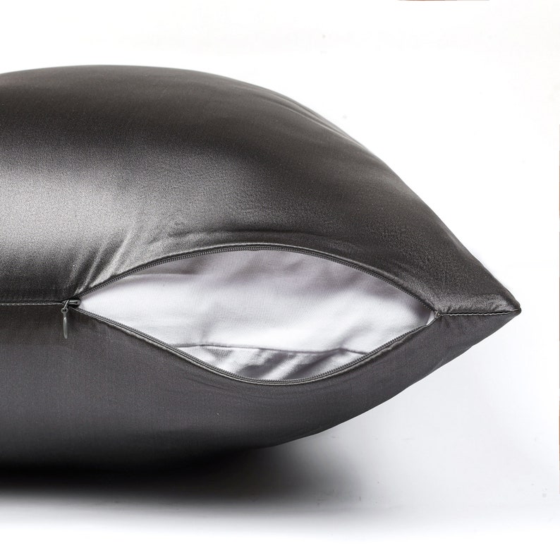 May include: A charcoal gray satin pillowcase with a zipper closure. The pillowcase is made of soft, luxurious fabric.