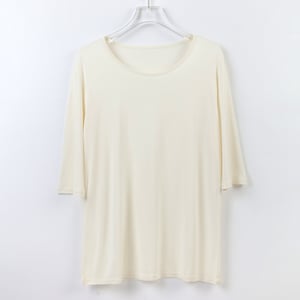 May include: A plain, off-white, long-sleeved t-shirt with a round neckline. The shirt is hanging on a white hanger against a white background.