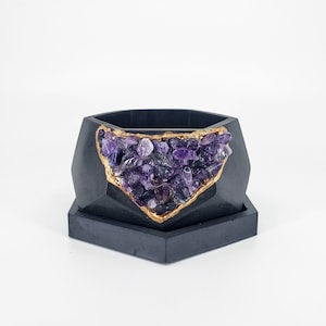 May include: A black hexagonal planter with a gold rim and a purple amethyst crystal geode design.  MADEBYYOURHANDS.COM is printed on the white background.