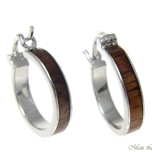 May include: A pair of silver hoop earrings with a brown wood inlay. The earrings have a hinged closure.