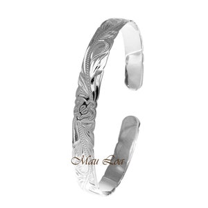 Puede incluir: Pulsera hawaiana de plata con un diseño floral. La pulsera está grabada con las palabras "Maui Loa".