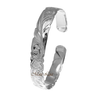 Könnte beinhalten: Ein silbernes Armband mit einem floralen Design. Das Armband ist aus poliertem Metall gefertigt und hat eine glatte Oberfläche.