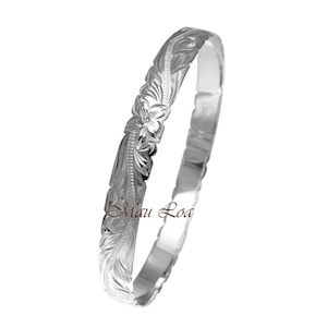 May include: A silver bangle bracelet with a floral design. The bracelet is engraved with the words "Maui Loa".